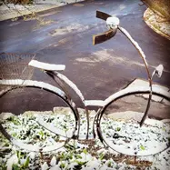 Ein mit Schnee bedecktes Metall-Fahrrad im Garten von MarVi
